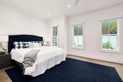a white bedroom with a bed and two windows at Sea Turtle Retreat in Seagrove Beach