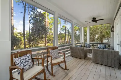 a screened porch with chairs and a ceiling fan at Waverly at Watersound in Watersound Beach