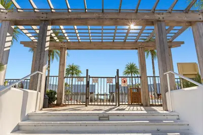 a wooden gate with palm trees in the background at Pet Friendly - Prominence on 30A by Panhandle Getaways in Watersound Beach