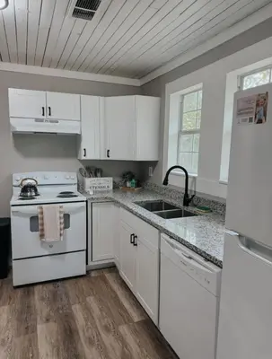 a kitchen with white cabinets and a stove and a sink at Coastal Farmhouse - Pet Friendly and Quiet Location in Southport