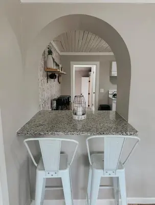 a kitchen with a counter with two white stools at Coastal Farmhouse - Pet Friendly and Quiet Location in Southport