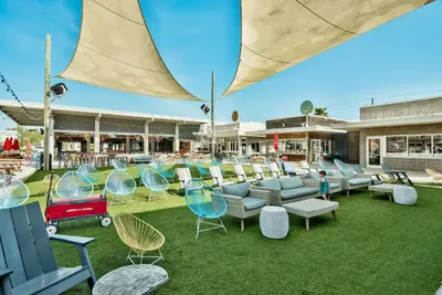 an outdoor patio with chairs and tables and an umbrella at Prominence on 30A Pet Friendly Rentals by Panhandle Getaways in Watersound Beach