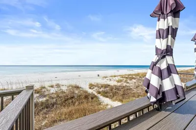 a deck with an umbrella and the beach at Southern Exposure Beach Home in Panama City Beach