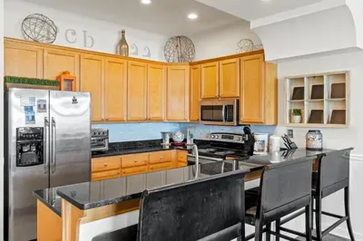 a kitchen with wooden cabinets and a stainless steel refrigerator at Southern Exposure Beach Home in Panama City Beach