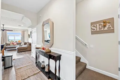 a living room with a staircase and a mirror at Southern Exposure Beach Home in Panama City Beach
