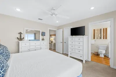 a white bedroom with a bed and a tv at Southern Exposure Beach Home in Panama City Beach