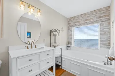 a white bathroom with a tub and a sink and a mirror at Southern Exposure Beach Home in Panama City Beach
