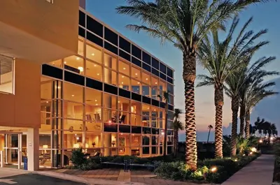 a large building with palm trees in front of it at Sterling Reef Beach Resort in Panama City Beach