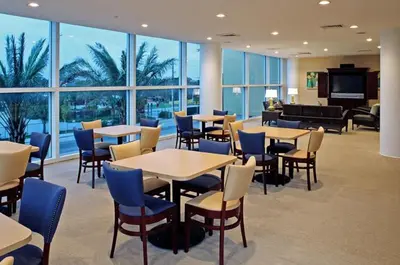 a restaurant with tables and chairs in a room with windows at Sterling Reef Beach Resort in Panama City Beach