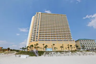 a large building on the beach with palm trees at Sterling Reef Beach Resort in Panama City Beach