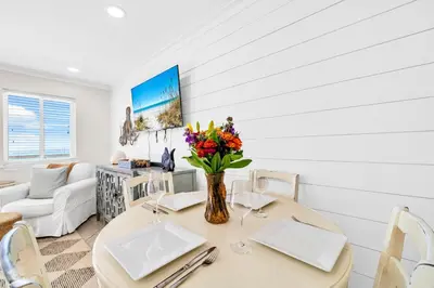 a dining room with a table with flowers in a vase at Book Me Baby! You are in Luck! I Am Gulf Front! in Santa Rosa Beach