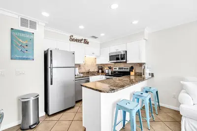 a kitchen with white cabinets and blue stools at Book Me Baby! You are in Luck! I Am Gulf Front! in Santa Rosa Beach