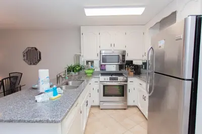a kitchen with white cabinets and a stainless steel refrigerator at 16 Chateau in Panama City Beach