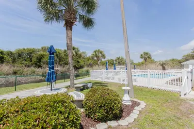 a garden with a palm tree and a blue umbrella at 16 Chateau in Panama City Beach