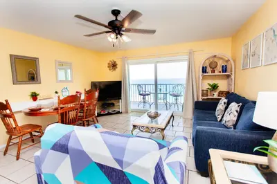 a living room with a blue couch and a table and chairs at Summit 903 in Panama City Beach