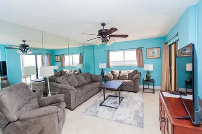 a living room with a couch and a tv at Regency 1023 in Panama City Beach