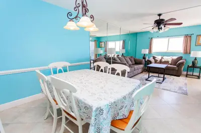 a dining room and living room with a table and chairs at Regency 1023 in Panama City Beach
