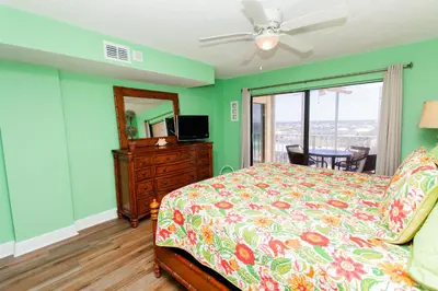 a bedroom with a bed and a dresser and a television at Regency 1023 in Panama City Beach