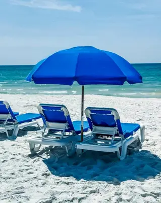three blue chairs and an umbrella on a beach at Summit 811 in Panama City Beach