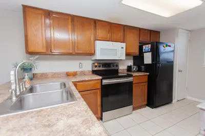 a kitchen with wooden cabinets and a black refrigerator at Moonspinner 808B in Panama City Beach