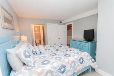 a bedroom with a bed with a blue dresser and a tv at Summit 627 in Panama City Beach