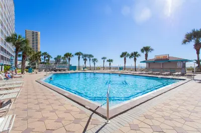 a large swimming pool with palm trees and a building at Summit 627 in Panama City Beach