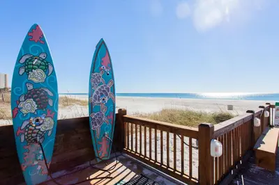 two surfboards are leaning against a wooden railing at the beach at Summit 627 in Panama City Beach