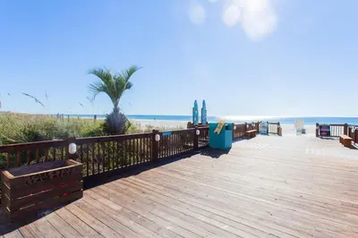 a wooden boardwalk leading to a beach with a palm tree at Summit 627 in Panama City Beach