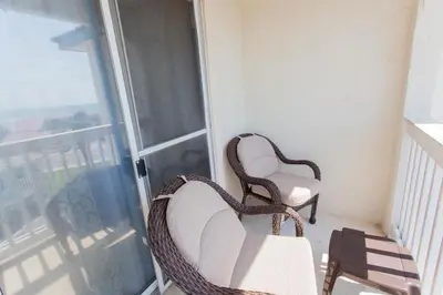 a balcony with a wicker chair and a window at Palms A4 Main in Panama City Beach