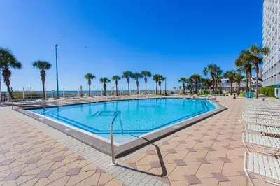 a swimming pool with palm trees and the ocean at Summit 203 in Panama City Beach