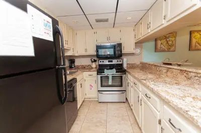 a kitchen with white cabinets and a black refrigerator at Sugar Beach E2 in Panama City Beach