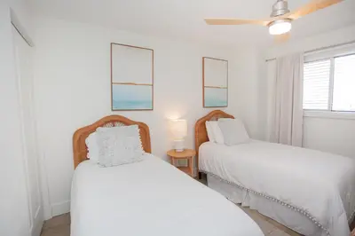 two beds in a white room with a window at Regency 501 in Panama City Beach
