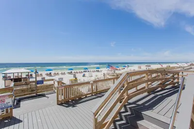 a boardwalk leading to the beach with chairs and umbrellas at Regency 501 in Panama City Beach