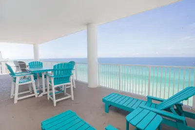 a balcony with blue chairs and a table with the ocean at Ocean Ritz 1501 in Panama City Beach