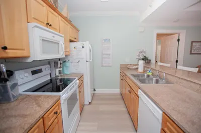 a kitchen with white appliances and wooden cabinets at Ocean Ritz 1501 in Panama City Beach