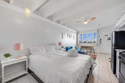 a white bedroom with a bed and a kitchen at Fontainebleau 428 in Panama City Beach