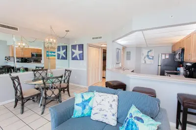 a living room with a blue couch and a kitchen at Summerhouse 1005a in Panama City Beach