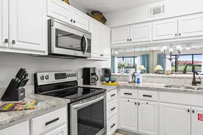 a kitchen with white cabinets and a stove top oven at Edgewater Golf Villas #3105 by Book That Condo in Panama City Beach