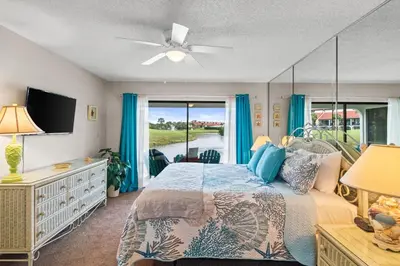 a bedroom with a bed and a window with blue curtains at Edgewater Golf Villas #3105 by Book That Condo in Panama City Beach