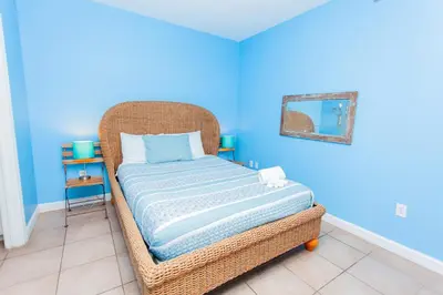 a wicker bed in a room with a blue wall at Shores of Panama 2220 in Panama City Beach