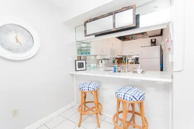 a kitchen with two bar stools and a clock at Mariner West 508 in Panama City Beach