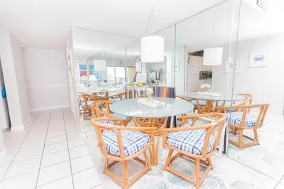 a dining room with tables and chairs and a mirror at Mariner West 508 in Panama City Beach