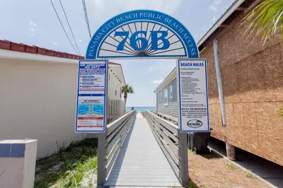 a boardwalk leading to the beach with two signs at Palms A4 Studio in Panama City Beach