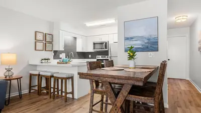 a kitchen and dining room with a wooden table and chairs at West End Coastal Escape Renovated 1BR Condo w Pool Beach Access 72 in Panama City Beach