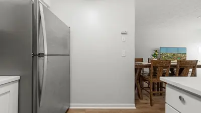 a stainless steel refrigerator in a kitchen with a table at West End Coastal Escape Renovated 1BR Condo w Pool Beach Access 72 in Panama City Beach