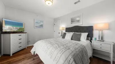 a white bedroom with a bed and a tv at West End Coastal Escape Renovated 1BR Condo w Pool Beach Access 72 in Panama City Beach