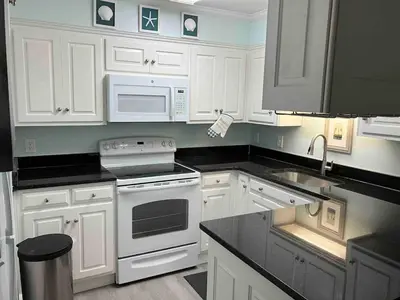 a kitchen with white cabinets and a white stove top oven at Make Your Getaway in Panama City Beach