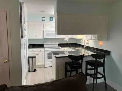 a kitchen with white cabinets and bar stools at Make Your Getaway in Panama City Beach
