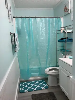 a bathroom with a blue shower curtain and a toilet at Make Your Getaway in Panama City Beach