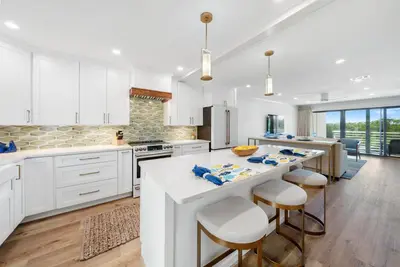 a kitchen with white cabinets and a large island with bar stools at 30A Hideaway l Ocean Views l Across street from beach l Rosemary Beach in Inlet Beach